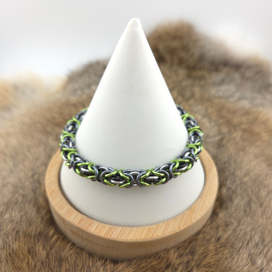 A handwoven Byzantine chainmail bracelet, woven in green, silver, gray, and black.