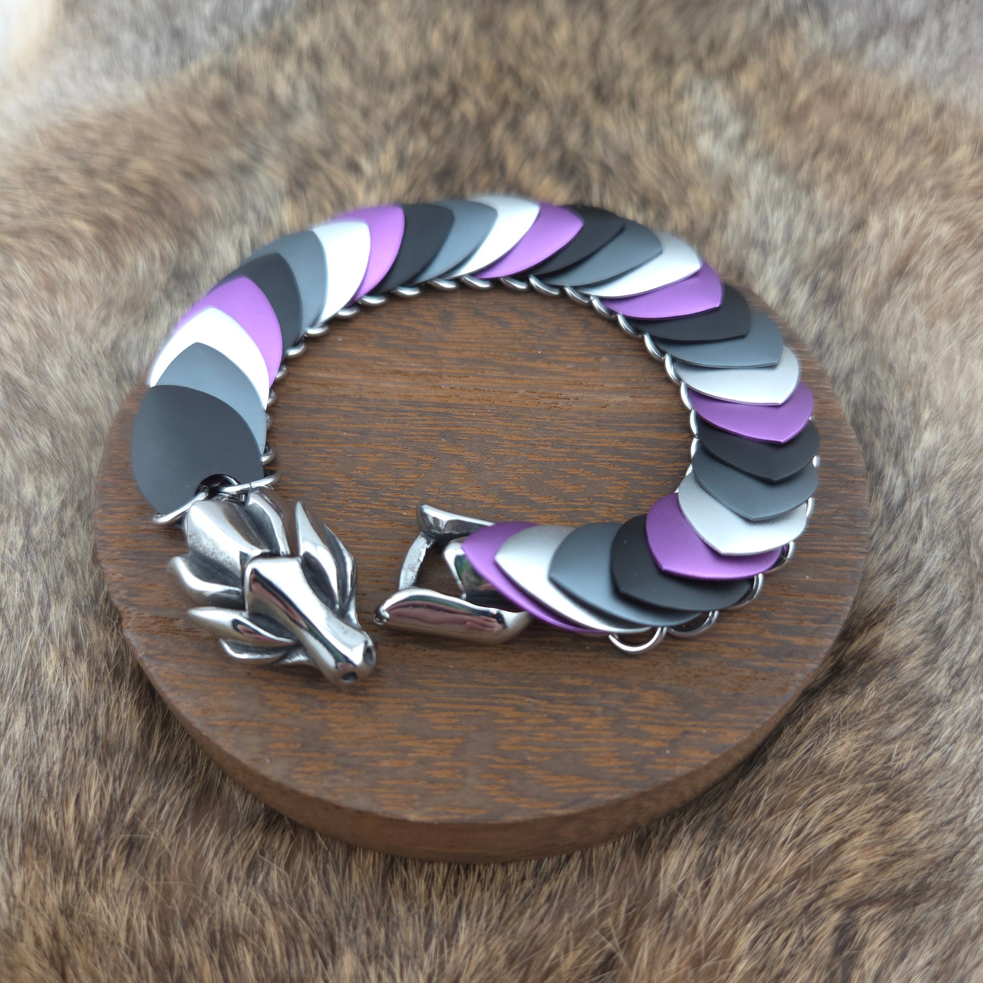 Dragon Scale Bracelet, with a stainless steel spine, premium anodized aluminum scales, and a solid stainless steel spring clasp shaped as a Dragon head.