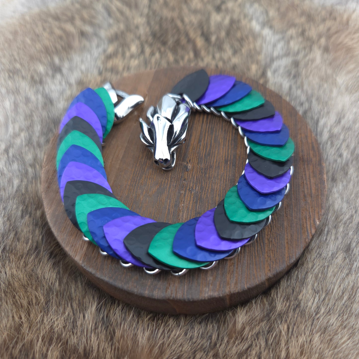 A dragon scale bracelet, handwoven with aluminum scales on a stainless steel spine with a solid stainless steel spring clasp.