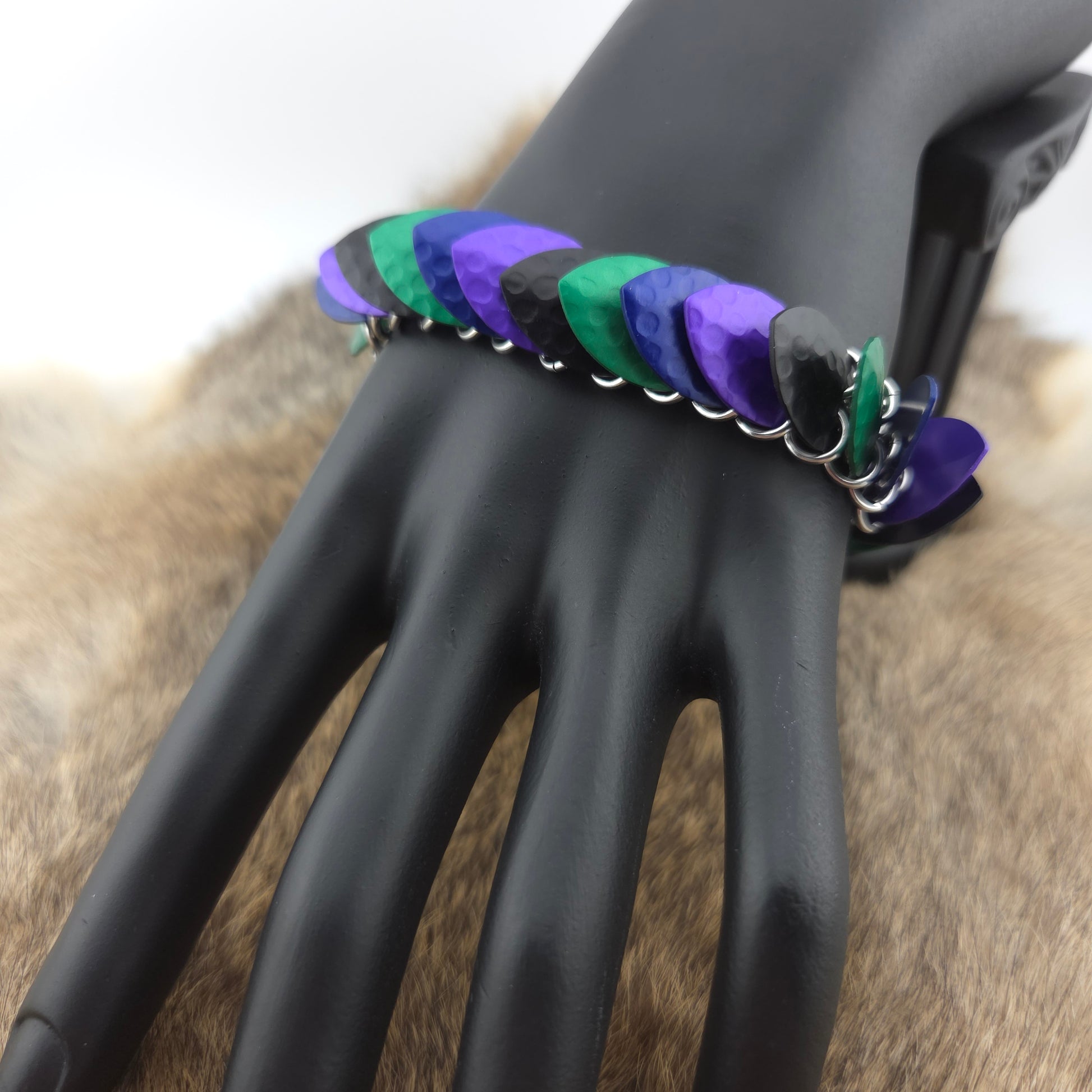 A dragon scale bracelet, handwoven with aluminum scales on a stainless steel spine with a solid stainless steel spring clasp.