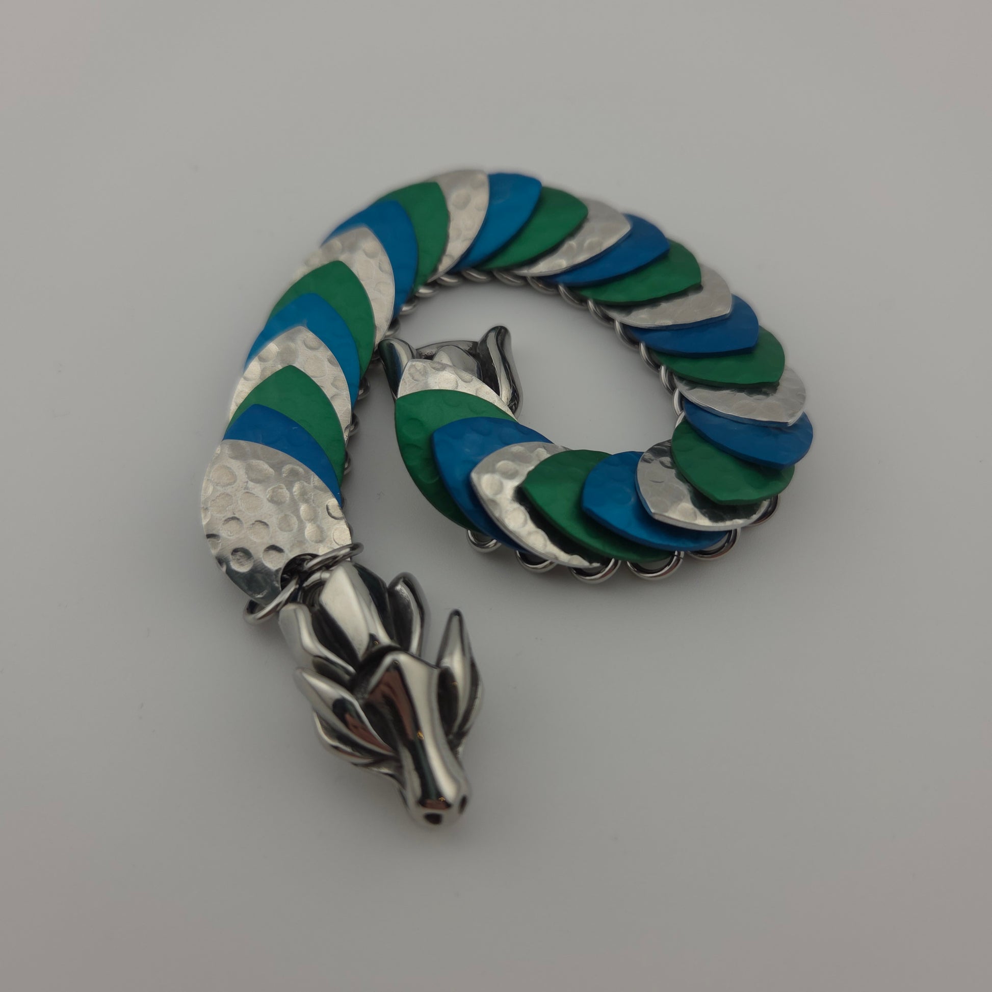 Dragon Scale Bracelet, with a stainless steel spine, premium anodized aluminum scales, and a solid stainless steel spring clasp shaped as a Dragon head.