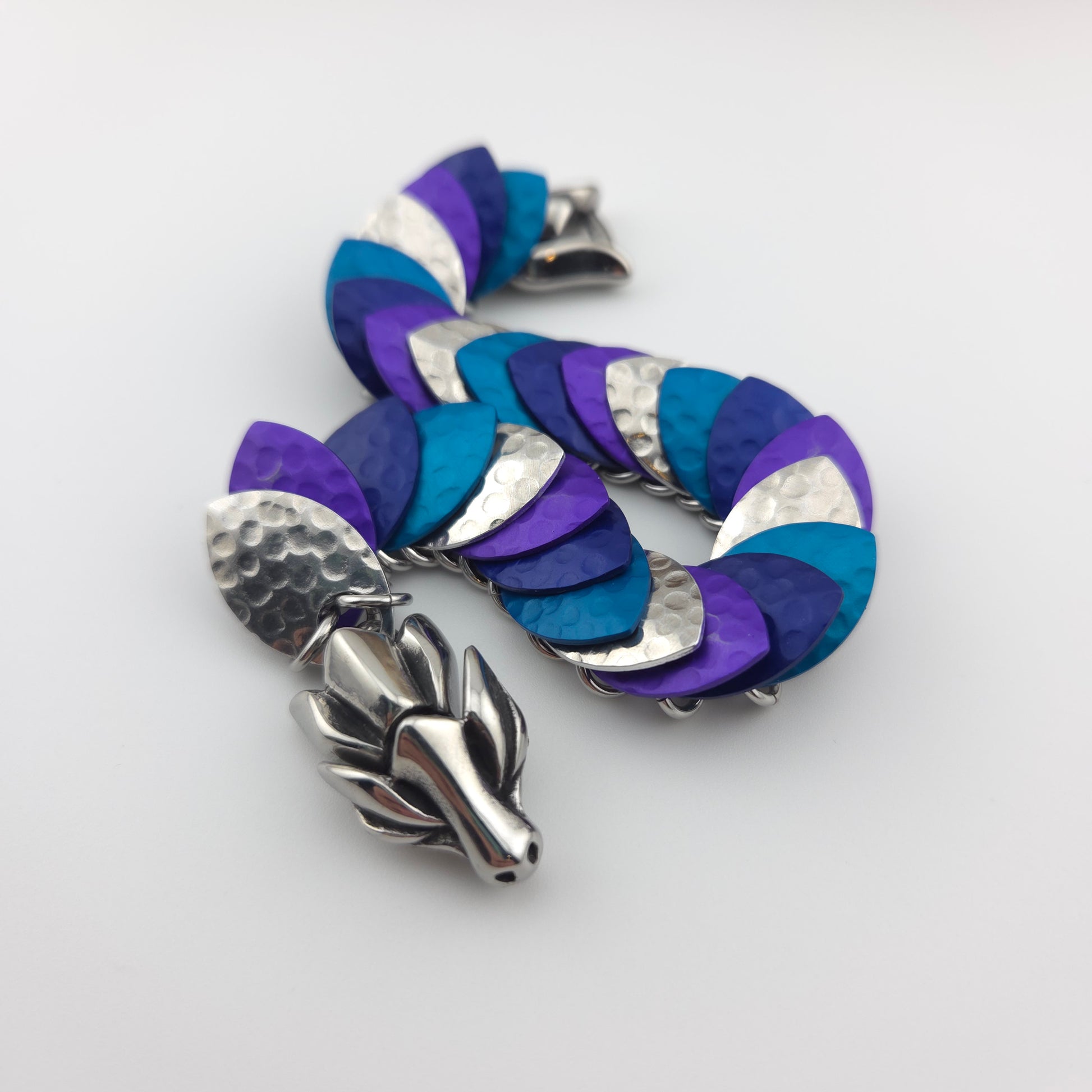 Dragon Scale Bracelet, with a stainless steel spine, premium anodized aluminum scales, and a solid stainless steel spring clasp shaped as a Dragon head.