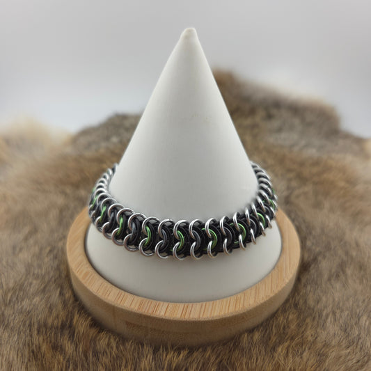 A vertebrae chainmail bracelet in Agender Pride Flag colors, green, gray, black, and silver.